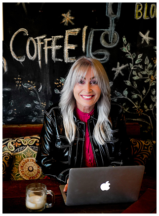 Annie Quinnell working on laptop at a local Port St. Lucie coffee shop, smiling and connecting with clients